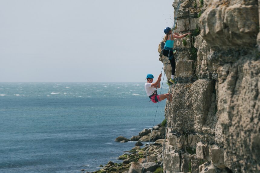 Young people climbing rock face