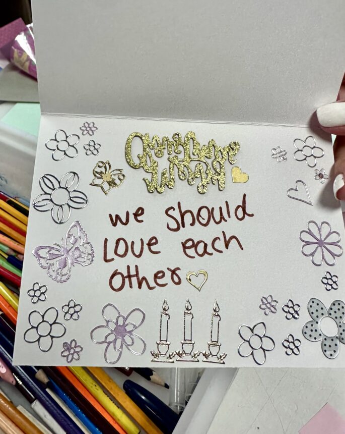 card which reads "we should love each other"